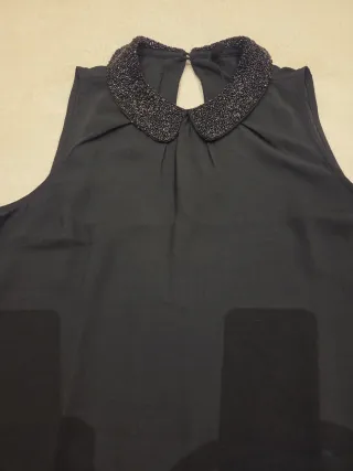 Blusa negra sin mangas con cuello adornado
