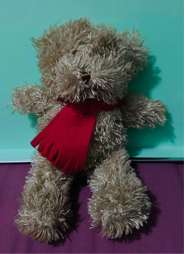 Osito de peluche marrón con bufanda roja