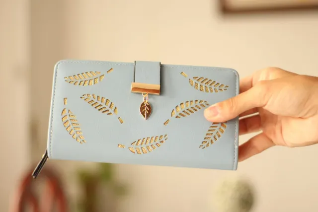Billetera azul con diseño de hojas doradas.
