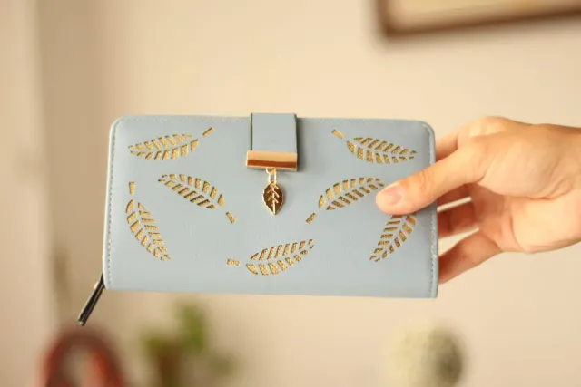 Billetera azul con diseño de hojas doradas.