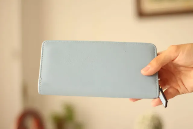 Billetera azul con diseño de hojas doradas.