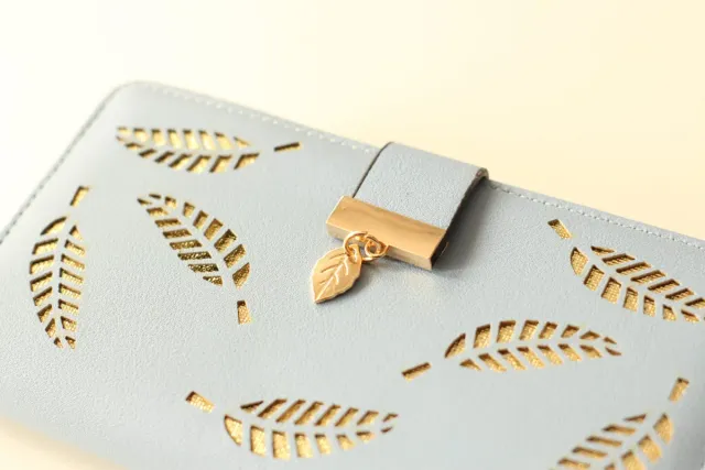 Billetera azul con diseño de hojas doradas.