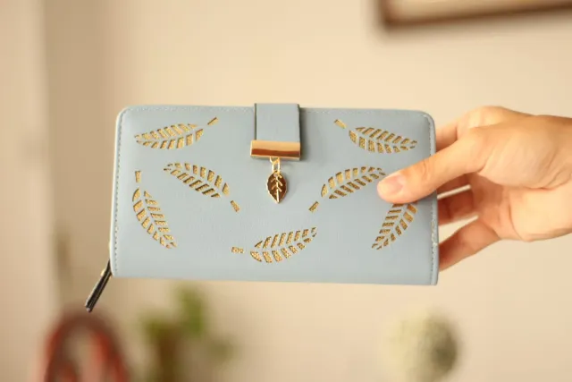 Billetera azul con diseño de hojas doradas.