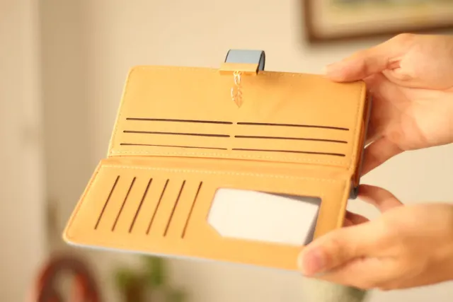 Billetera azul con diseño de hojas doradas.