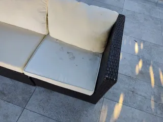 Sofá exterior de mimbre marrón y cojines blancos