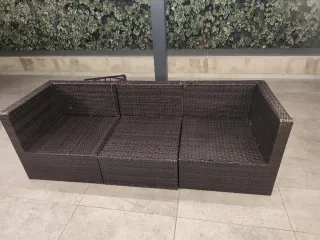 Sofá exterior de mimbre marrón y cojines blancos