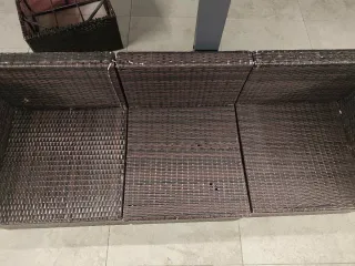 Sofá exterior de mimbre marrón y cojines blancos