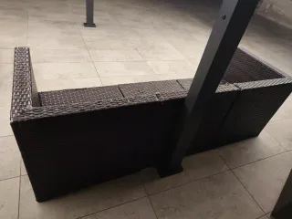 Sofá exterior de mimbre marrón y cojines blancos