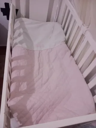 Cuna de bebé blanca con mosquitera