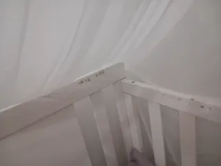 Cuna de bebé blanca con mosquitera