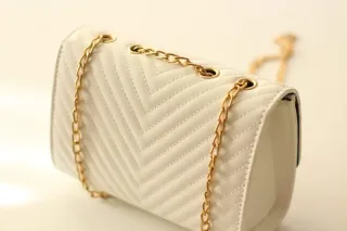 Bolso blanco con detalles dorados.