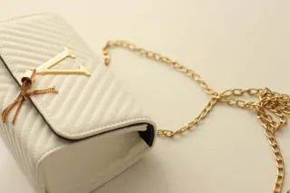 Bolso blanco con detalles dorados.