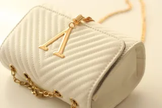 Bolso blanco con detalles dorados.