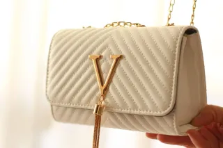 Bolso blanco con detalles dorados.