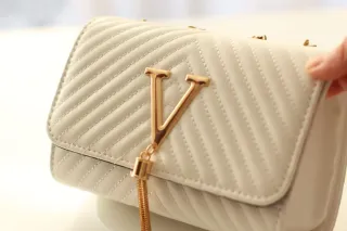 Bolso blanco con detalles dorados.
