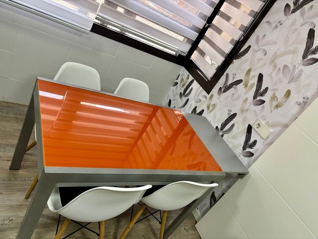 Mesa de cocina de cristal naranja y metal gris.