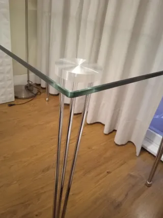 Mesa de cristal con patas metálicas.