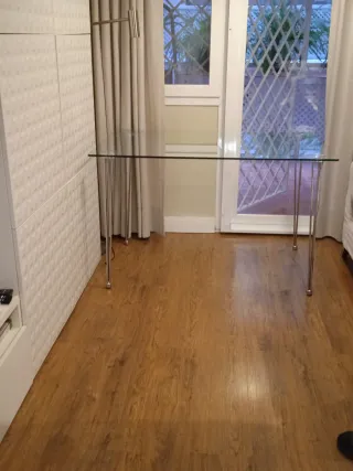 Mesa de cristal con patas metálicas.