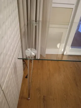 Mesa de cristal con patas metálicas.