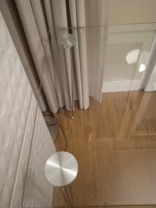 Mesa de cristal con patas metálicas.