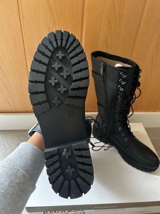 Botas altas negras con cordones y hebillas.