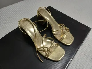 Sandalias doradas, con tacón. De Mango