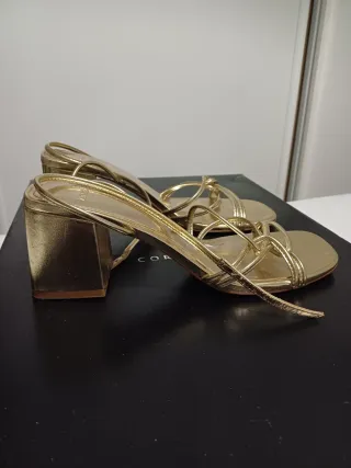 Sandalias doradas, con tacón. De Mango