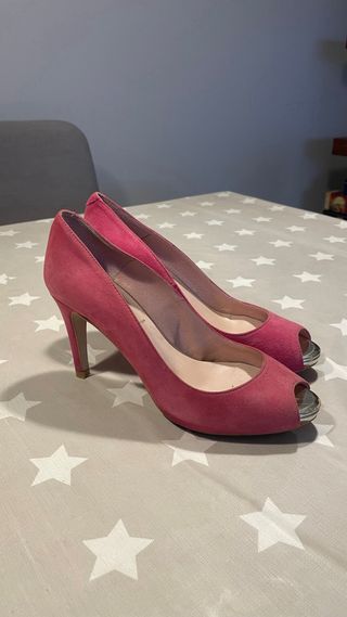 Zapatos de tacón rosas de ante con punta dorada.