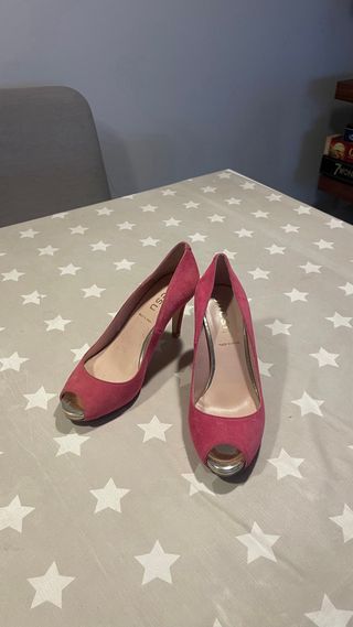 Zapatos de tacón rosas de ante con punta dorada.