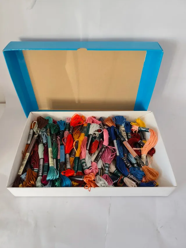 Caja con 56 hilos de bordar nuevos.