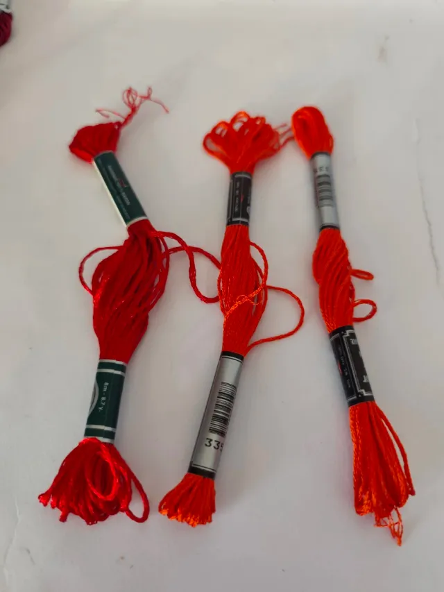 Caja con 56 hilos de bordar nuevos.