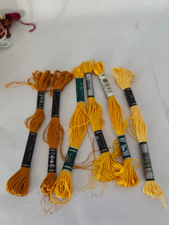 Caja con 56 hilos de bordar nuevos.