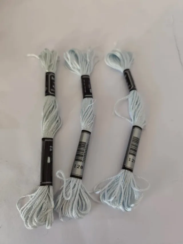 Caja con 56 hilos de bordar nuevos.