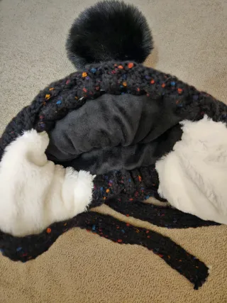 Gorro negro con pompón, orejeras y forro polar.