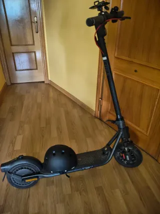 Patinete eléctrico negro con casco y 2 cargadores