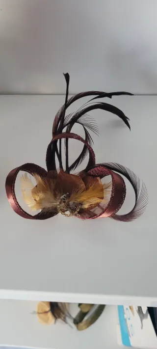 Tocado lazo burdeos y plumas doradas