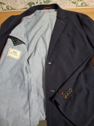 Americana azul marino, con coderas en marrón.