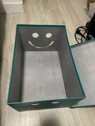 Caja de almacenaje azul con cara sonriente.