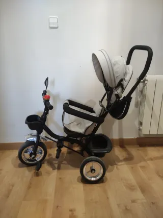 Triciclo infantil con capota y manillar.