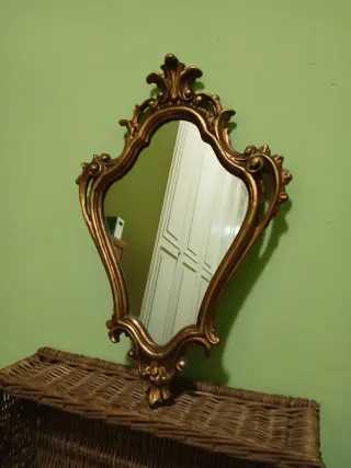 Specchio vintage con cornice in legno dorata.