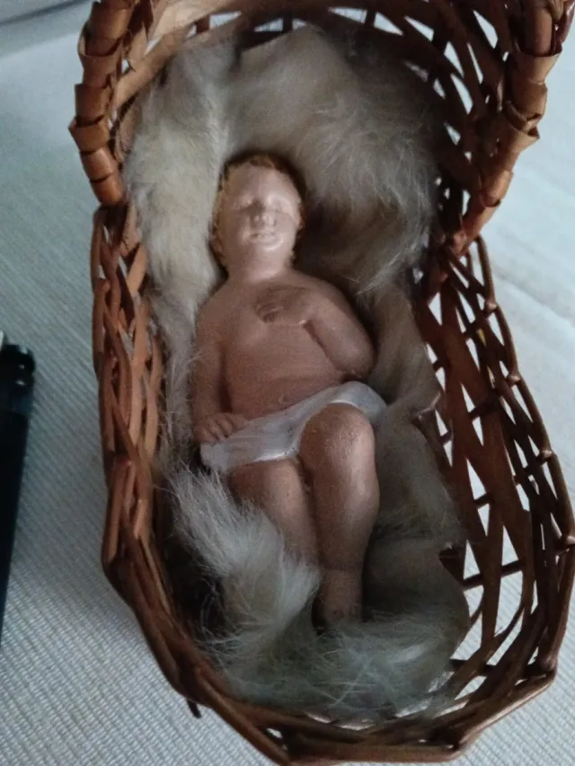 Niño Jesús artesanal en cunita de mimbre.