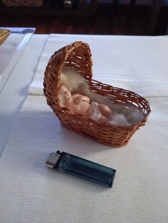 Niño Jesús artesanal en cunita de mimbre.
