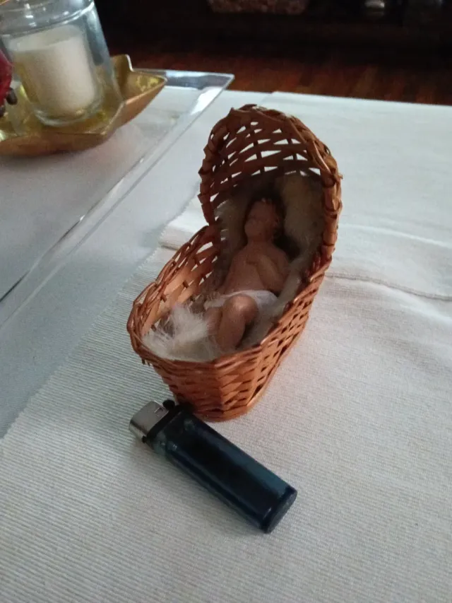 Niño Jesús artesanal en cunita de mimbre.