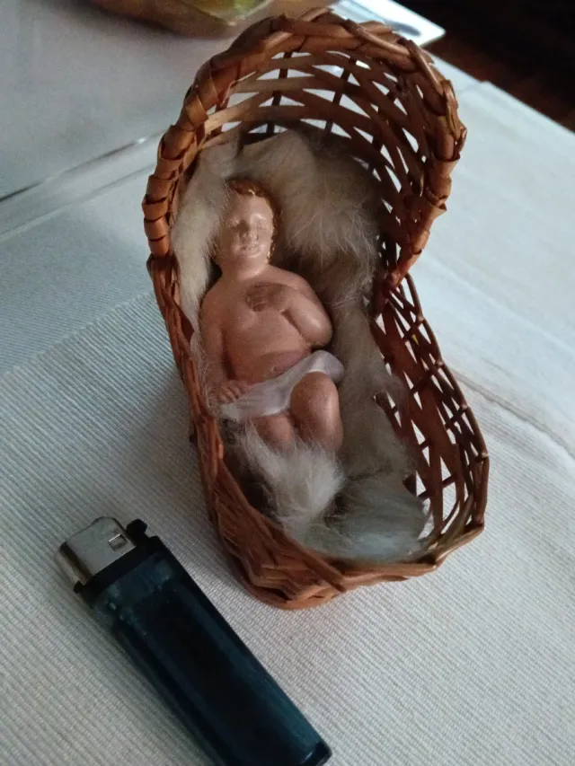 Niño Jesús artesanal en cunita de mimbre.
