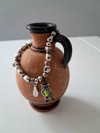 Pulsera plateada, con búho y pluma.