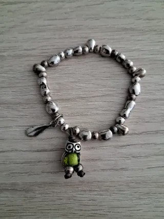 Pulsera plateada, con búho y pluma.