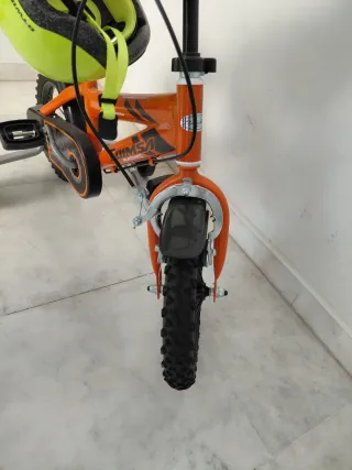 Bicicleta infantil naranja con casco