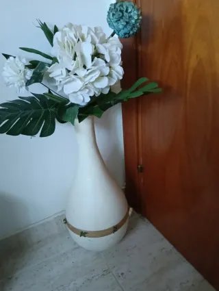 Jarrón blanco con flores y tapete