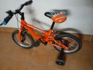 Bicicleta infantil naranja con ruedines