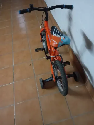 Bicicleta infantil naranja con ruedines